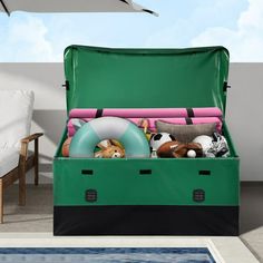 an open green trunk filled with toys next to a swimming pool