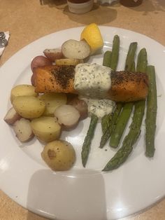 a white plate topped with asparagus, potatoes and other food on top of it