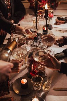 a group of people sitting at a table with wine glasses and candles in front of them