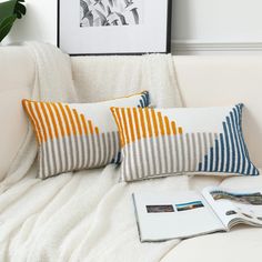 two striped pillows on a white couch next to an open book and potted plant