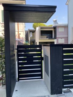 an open gate in the middle of a sidewalk next to a building with two balconies