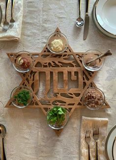 the star of david is made out of wood and has silverware on it, along with other place settings