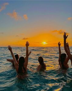 three girls in the water playing with a frisbee at sunset or sunrise time