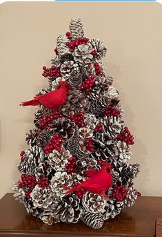 a christmas tree made out of pine cones and red cardinals on it's branches