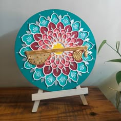 a wooden table with a blue and red plate on top of it next to a potted plant