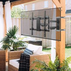 an outdoor living area with wicker furniture and large flat screen tv mounted to the wall