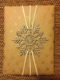 a snowflake on top of a brown paper with silver sparkles in the middle