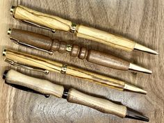 three different types of wooden pens sitting on top of a wood table next to each other