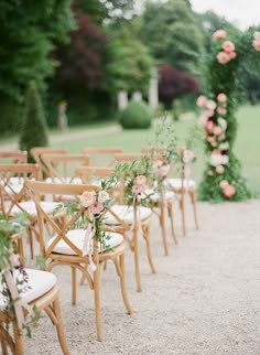 the chairs are lined up with flowers and greenery at the end of the aisle