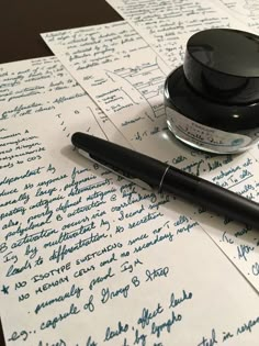 a pen and ink sitting on top of a piece of paper with handwritten letters