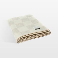 a white and beige blanket folded on top of each other with a black tag in the middle