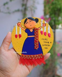 a hand holding up a small magnet with a woman in a blue dress on it