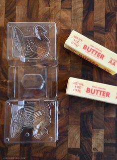 three butter cutters sitting on top of a wooden table next to two packages of butter