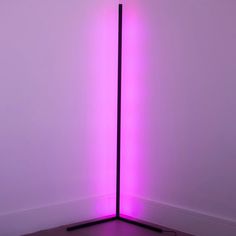 a purple light is shining in the corner of a room with a black floor lamp