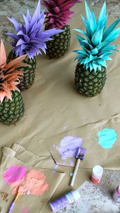 three pineapples with blue and pink flowers sitting on top of a piece of paper