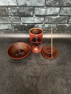 three wooden bowls and two candlesticks sitting next to a brick wall