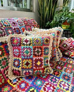 two crocheted pillows sitting on top of a bed next to a potted plant