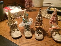 four pairs of baby shoes sitting on top of a wooden table next to some candy