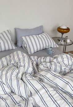 an unmade bed with blue and white striped sheets