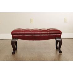 a red leather bench sitting on top of a hard wood floor