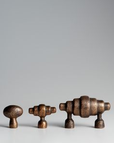 three wooden knobs are lined up against a gray background, one is turned upside down