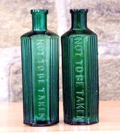 two green glass bottles sitting on top of a wooden table