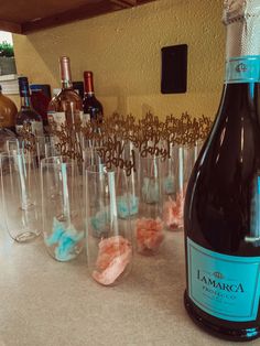 a bottle of wine sitting on top of a counter next to glasses filled with candy