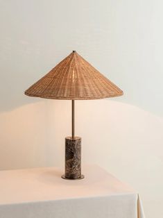 a table lamp sitting on top of a white tablecloth covered table next to a wall