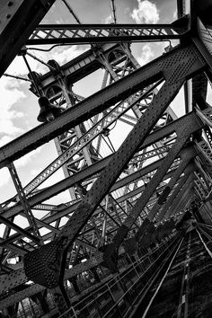 black and white photograph of steel structure with sky in background, taken from ground level