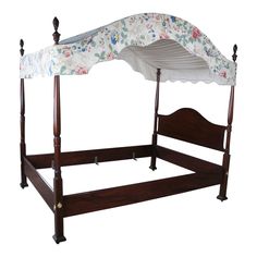 a wooden bed with a white canopy and flowers on the top, against a white background