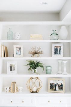 a white book shelf filled with books and vases