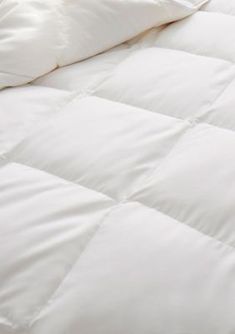 an unmade bed with white sheets and pillows