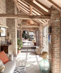 a living room filled with furniture and lots of windows next to a brick wall covered in wood