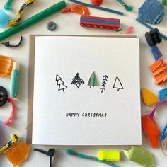 a white card with the words happy christmas on it surrounded by various crafting supplies