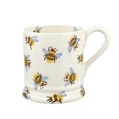 a white mug with yellow bees printed on the outside and inside, sitting in front of a white background