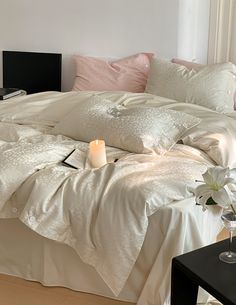 a bed with white sheets and pillows on top of it next to a vase filled with flowers