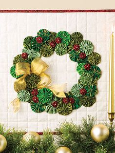 a christmas wreath is hanging on the wall next to a candle and some green decorations