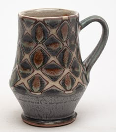 a brown and black vase sitting on top of a white table