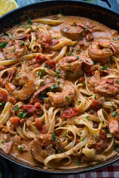 pasta with shrimp and tomato sauce in a skillet on a checkered table cloth