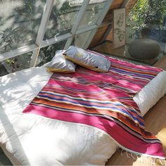 a bed sitting on top of a wooden floor next to a glass wall covered in plants