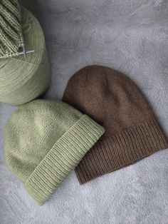 two knitted hats sitting next to each other on top of a white surface,