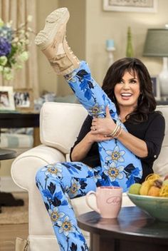 a woman sitting on a couch with her legs up in the air while holding a coffee mug