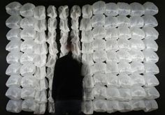 a man standing in front of a wall made out of plastic bags and white cloths