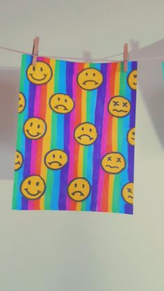 there are many different colored emoticions on this rainbow striped wall hanging from the clothesline