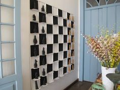 a vase filled with flowers sitting on top of a table next to a wall mounted shelf