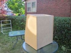 a cardboard box sitting on top of a table in front of a brick building and green grass