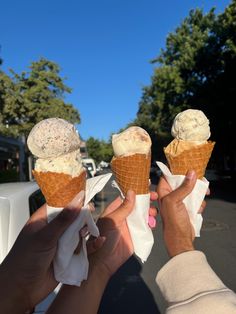 two people holding ice cream cones in their hands