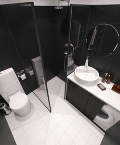 a black and white bathroom with a toilet, sink, mirror and shower stall in it