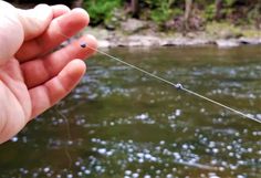 a person holding a fishing line in their hand next to a body of water with small bubbles on it