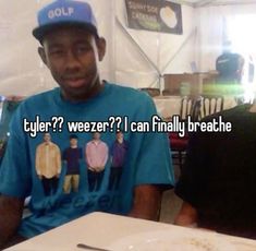 a man sitting at a table with a plate of food in front of him that says tyler? weezer? i can finally breathe